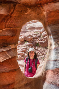 Portrait of smiling woman looking through rock formation