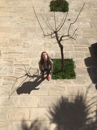 Portrait of smiling young woman standing against tree