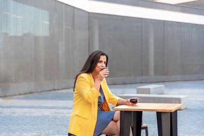 Woman looking at camera while sitting on mobile phone