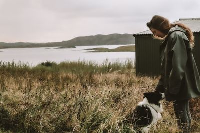 Woman with dog by standing by lake