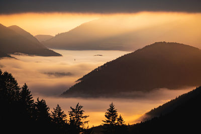 Scenic view of silhouette mountains against orange sky