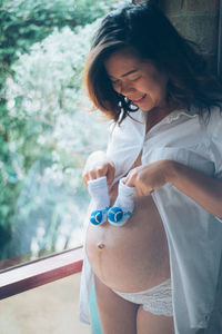 Pregnant woman holding baby booties against belly