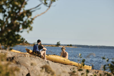 Men sitting near kayaks at rocky coast