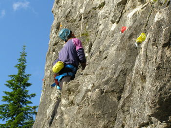 Low angel view of man climbing on rocky mountain