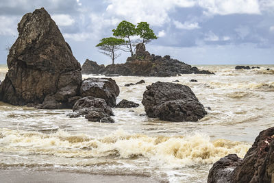 Rock formation on beach against sky