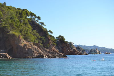 Scenic view of sea and mountains against clear blue sky