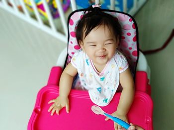 High angle view of baby girl sitting on high chair at home