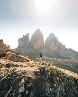 Man on rocks by mountains against sky