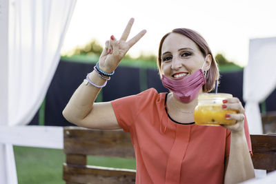 Portrait of smiling young woman with arms raised