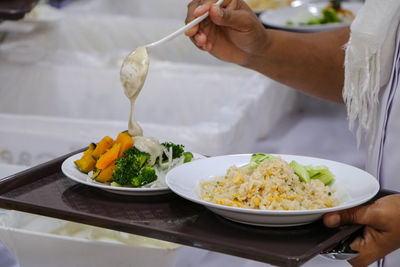 Woman holding food in plate on table