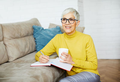 Thoughtful woman writing in book at home