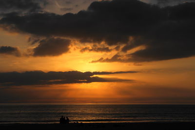 Scenic view of sea against dramatic sky during sunset