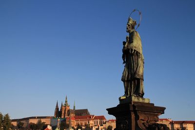 Low angle view of statue and castle against blue sky