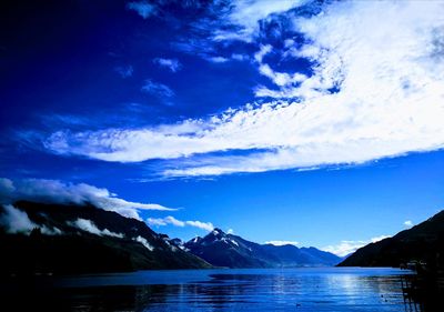 Scenic view of lake and mountains against blue sky