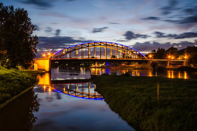 Arch bridge over river against sky at sunset