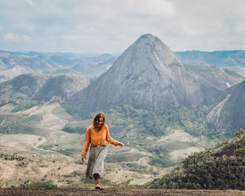 Rear view of woman standing on mountain against sky