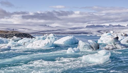 Ice floating on sea against sky during winter