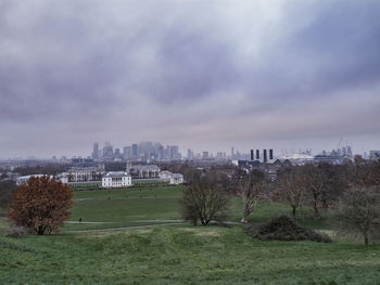 Scenic view of field by buildings against sky