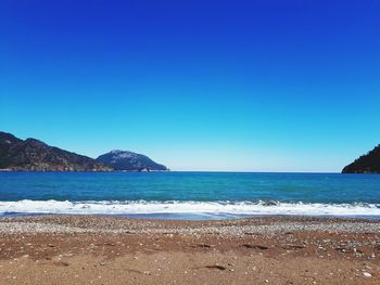 Scenic view of beach against clear blue sky