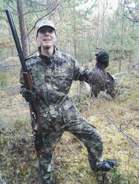 Portrait of smiling young man with arms outstretched standing against trees