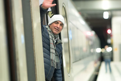 Man waving hand while standing in train