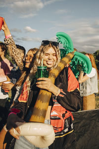 Happy woman holding balloon while enjoying drink with friends at music festival