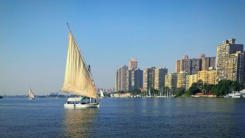 Sailboats sailing in sea against clear blue sky