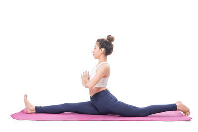 Full length of woman exercising against white background