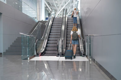 Woman standing on escalator in building