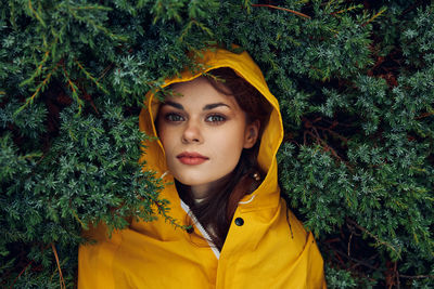 Portrait of young woman standing against plants