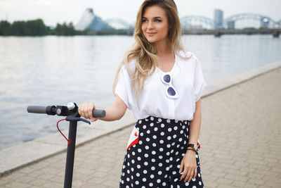 Portrait of young woman standing against lake