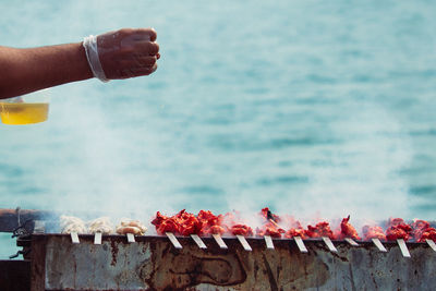 Midsection of person holding ice cream against sea