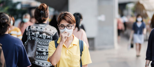 Woman with pollution mask coughing in city