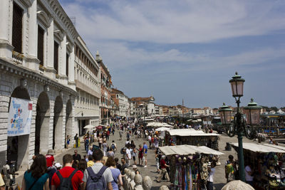 People on street amidst buildings in city against sky