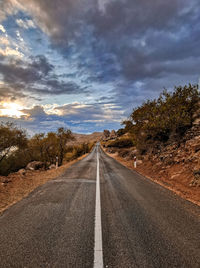 Road passing through landscape against cloudy sky