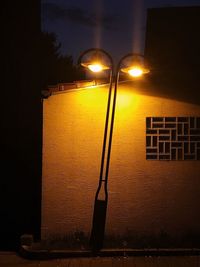 Illuminated street light against yellow sky at night