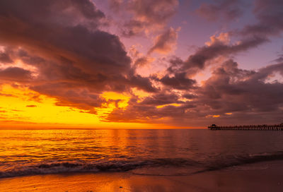 Scenic view of sea against dramatic sky during sunset