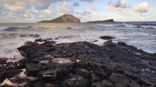Rock formation on beach against sky