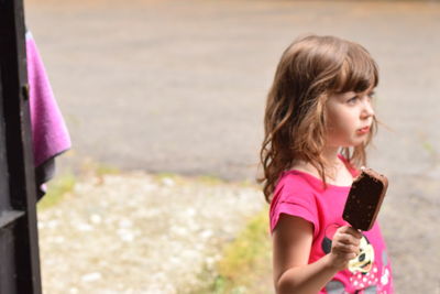 Cute girl holding ice cream while standing on street