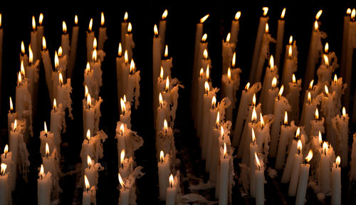 Close-up of illuminated candles against black background