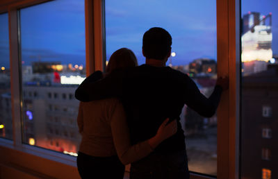 Silhouette of woman looking through window