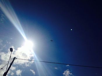 Low angle view of sun shining through clouds