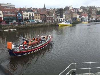 Boats in river by buildings in city