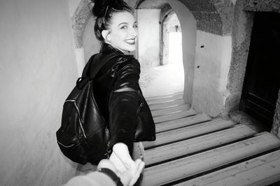 Portrait of happy woman standing on staircase