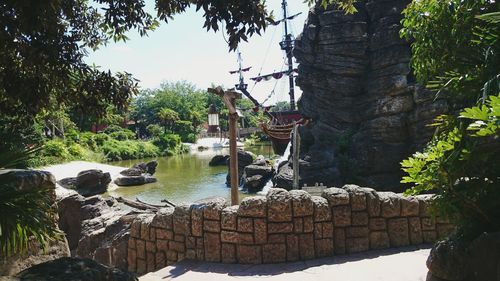 Stone wall by rocks against sky