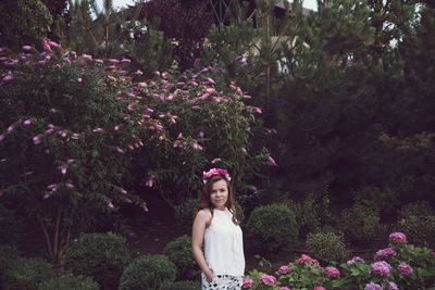 Portrait of young woman standing amidst plants at park