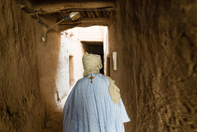 Rear view of man walking amidst old walls