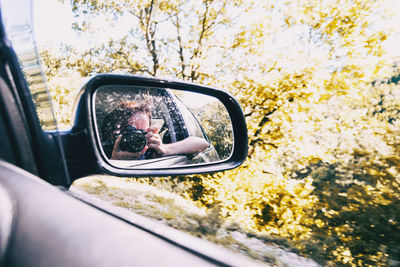 Reflection of man on side-view mirror