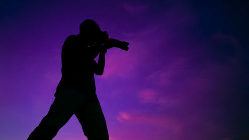 Low angle view of silhouette woman standing against sky during sunset