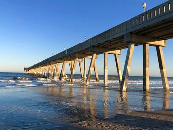 Pier over sea against clear blue sky